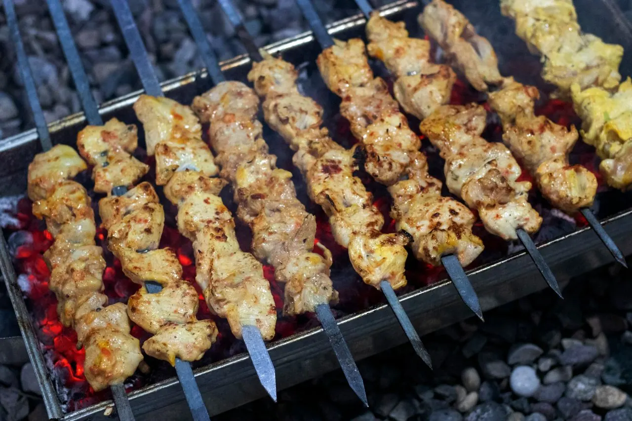 Chicken kebabs grilling over hot coals (illustrative photo)