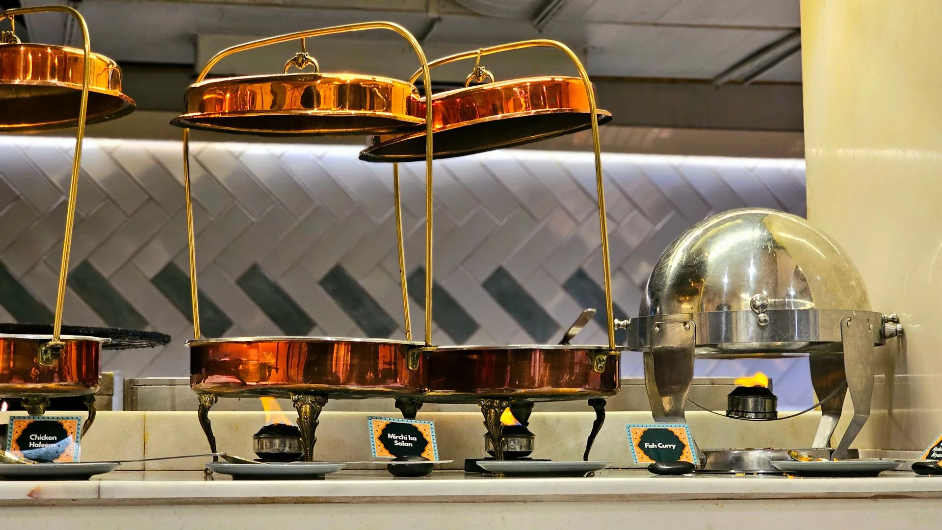 Copper buffet warmers with chicken haleem, mirchi ka salan and fish curry at a premium Indian catering setup (illustrative photo)