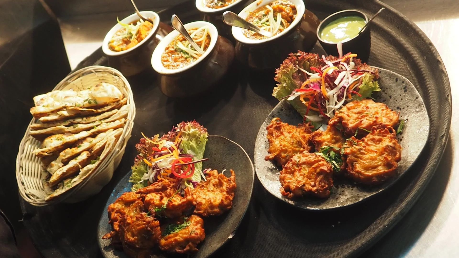 Indian catering sharing platter with handi curries, pakoras and naan (illustrative photo)