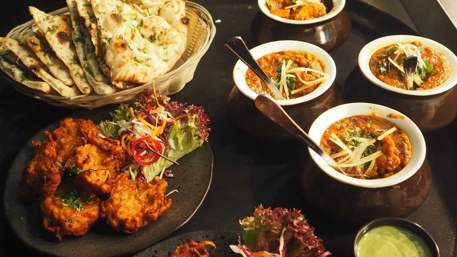 Handi curries with naan and pakoras at an Indian buffet counter (illustrative photo)