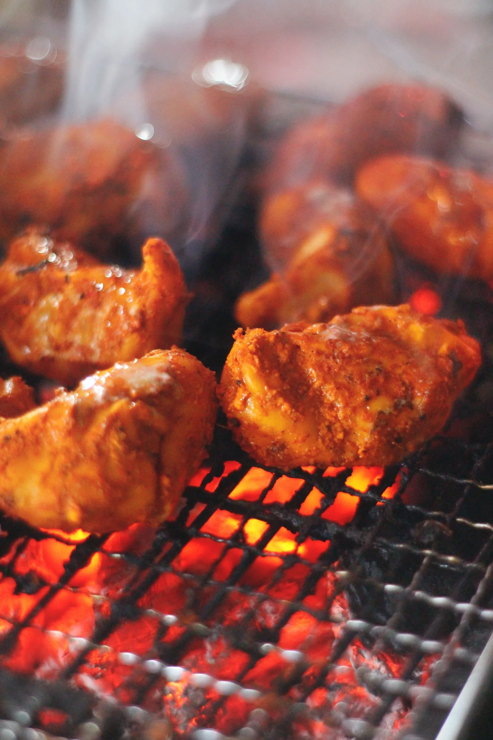 Tandoori chicken grilling over coals at a live Indian kebab counter (illustrative photo)