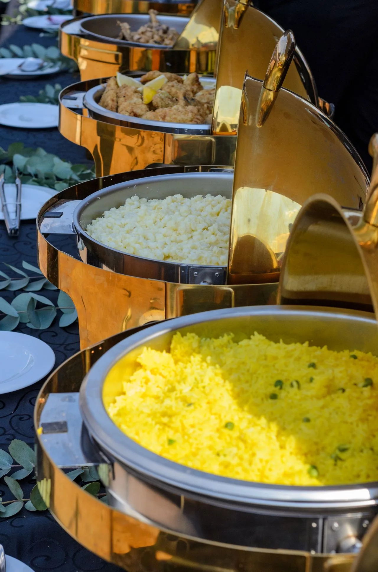 Premium wedding buffet with golden chafing dishes of pulao rice and starters (illustrative photo)